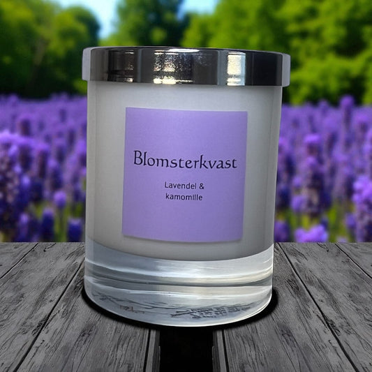 Hvit glassbeholder med sølvlokk som inneholder duftlys