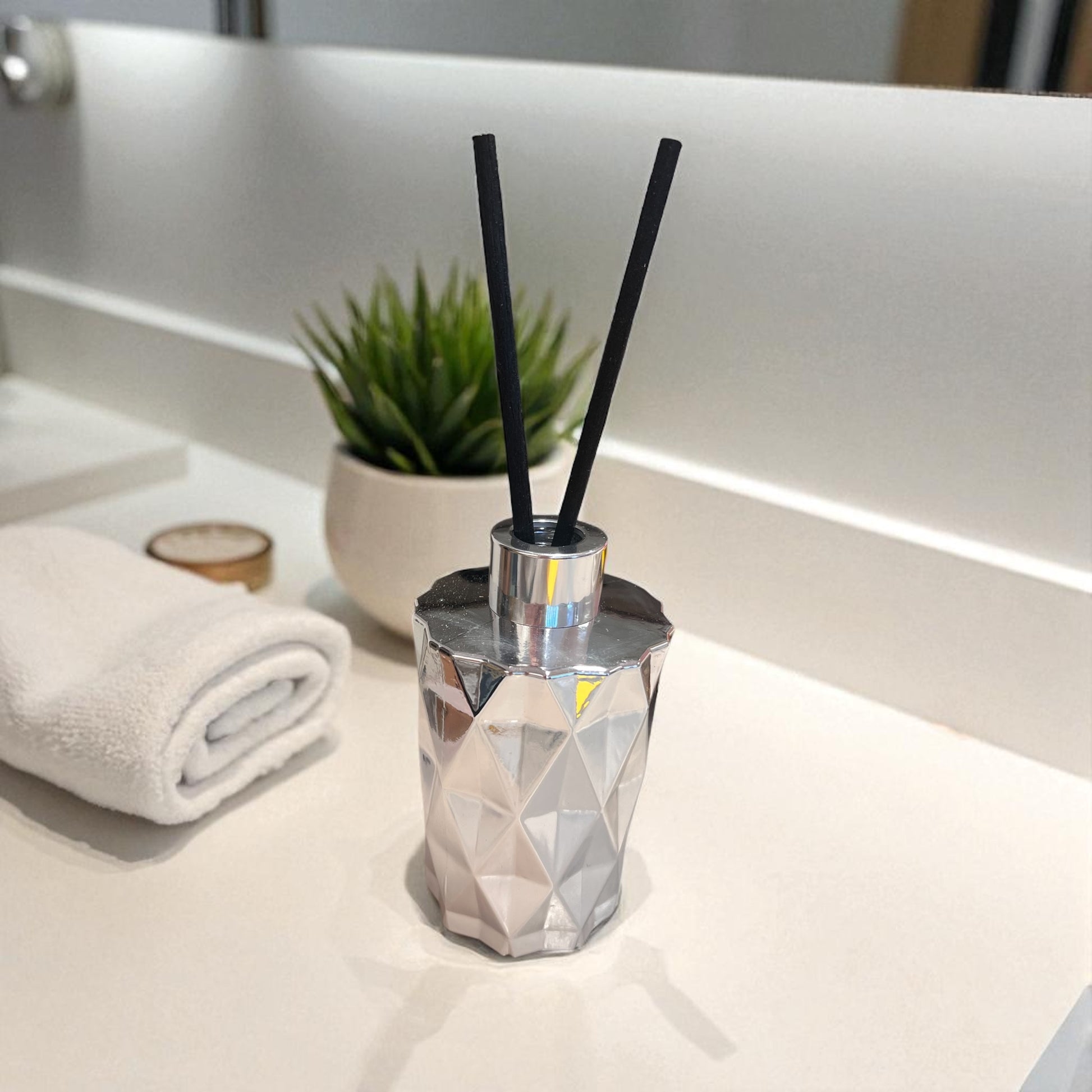 Sølvfarget duftpinnebeholder med sorte pinner