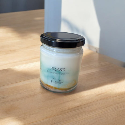 Glassbeholder med svart lokk, inneholder oransje og grønt duftlys