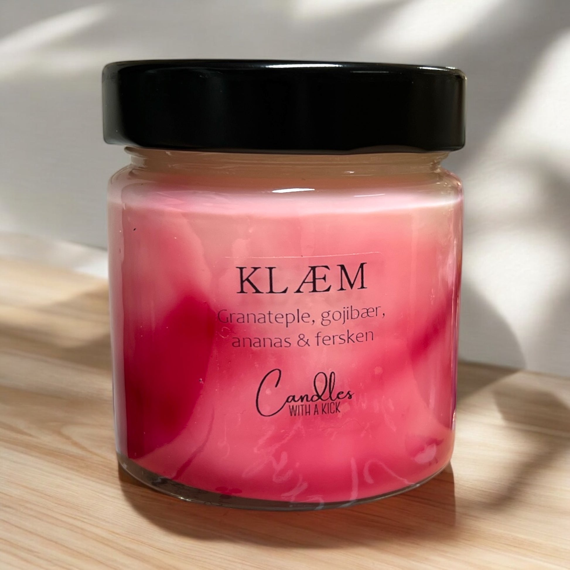 Glassbeholder med svart lokk, inneholder duftlys med rosa farge