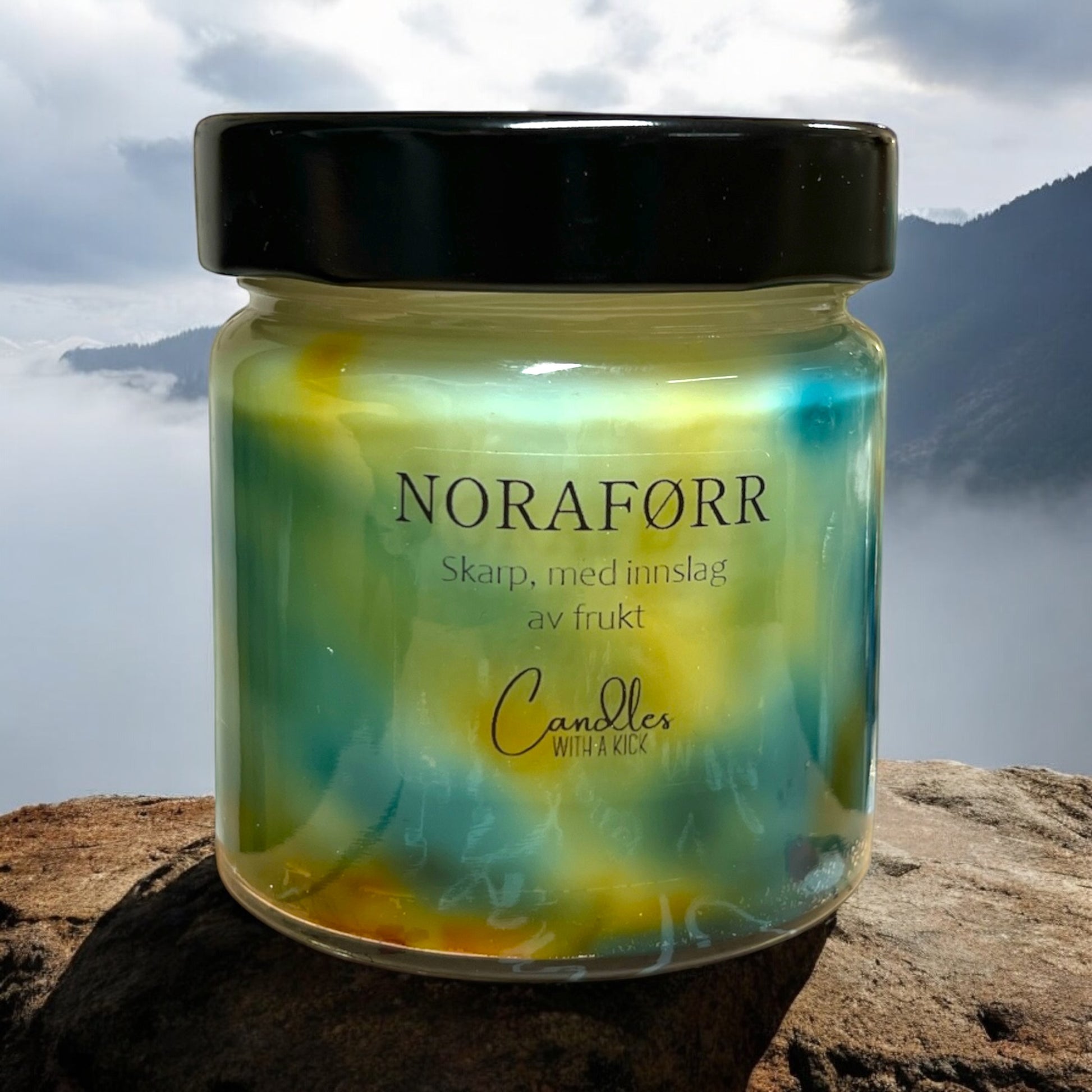 Glassbeholder med svart lokk, inneholder duftlys med oransje og teal farge