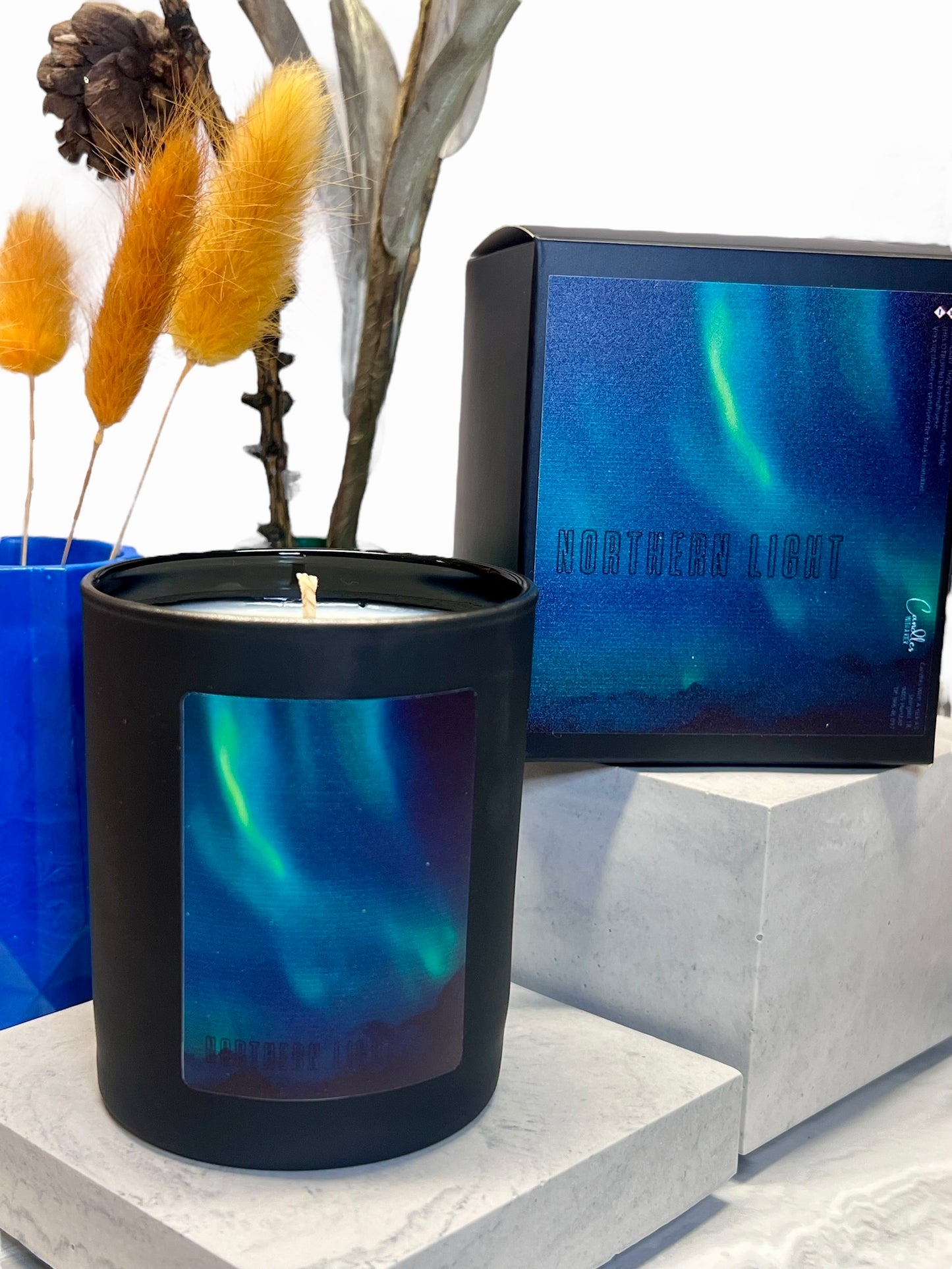 Svart glassbeholder som inneholder duftlys med etikett med nordlys